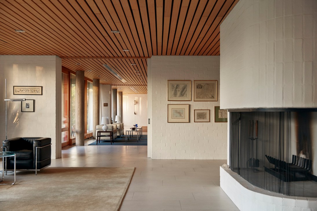 Open plan living area with wooden slatted ceiling, mid-century furniture, and floor-to-ceiling windows