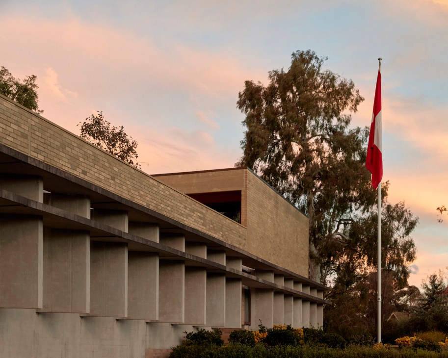 Swiss embassy in Canberra showing modernist concrete architecture with columns and red flag at dusk