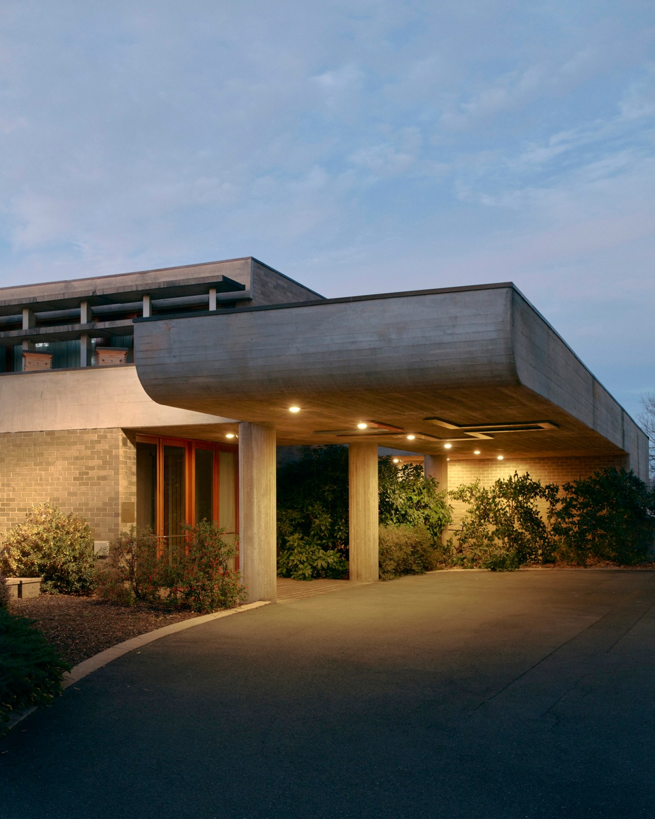 Dramatic concrete cantilevered overhang at embassy entrance creating geometric shadow patterns