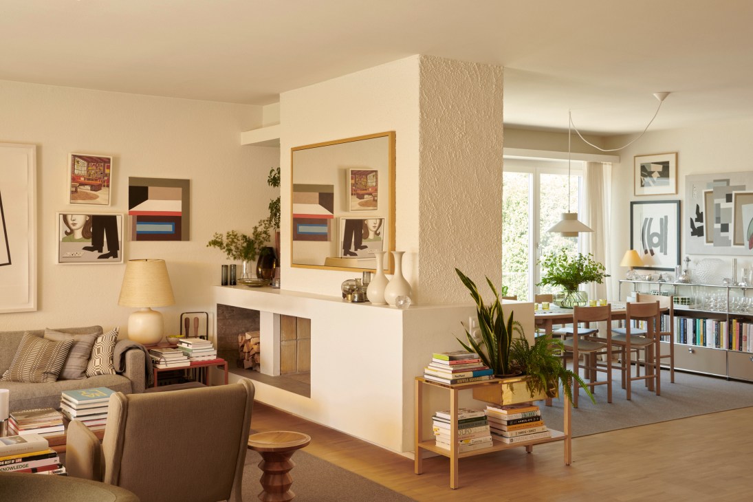 Open-plan living room with built-in white fireplace, gray sofa, wooden coffee table, and framed artwork on walls