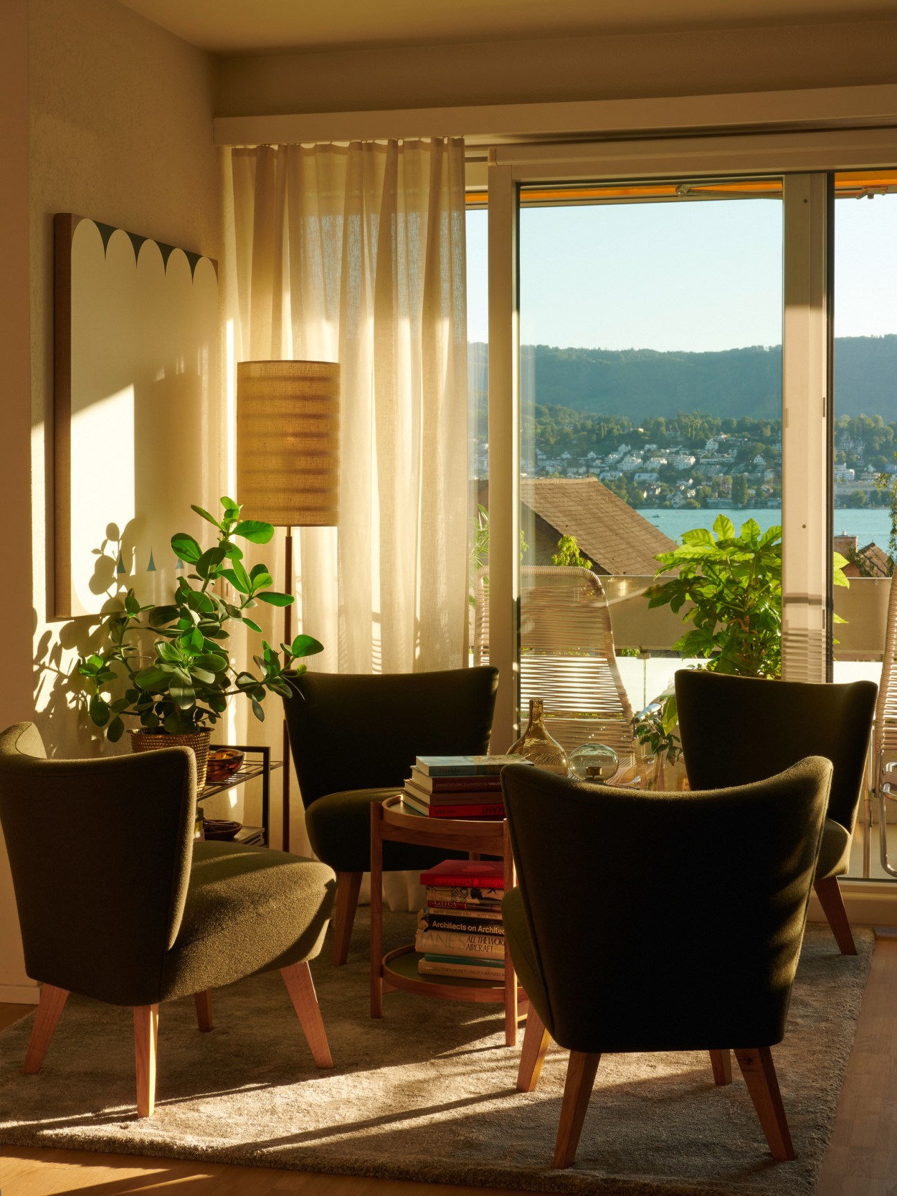 Green upholstered chairs positioned by large windows overlooking lake