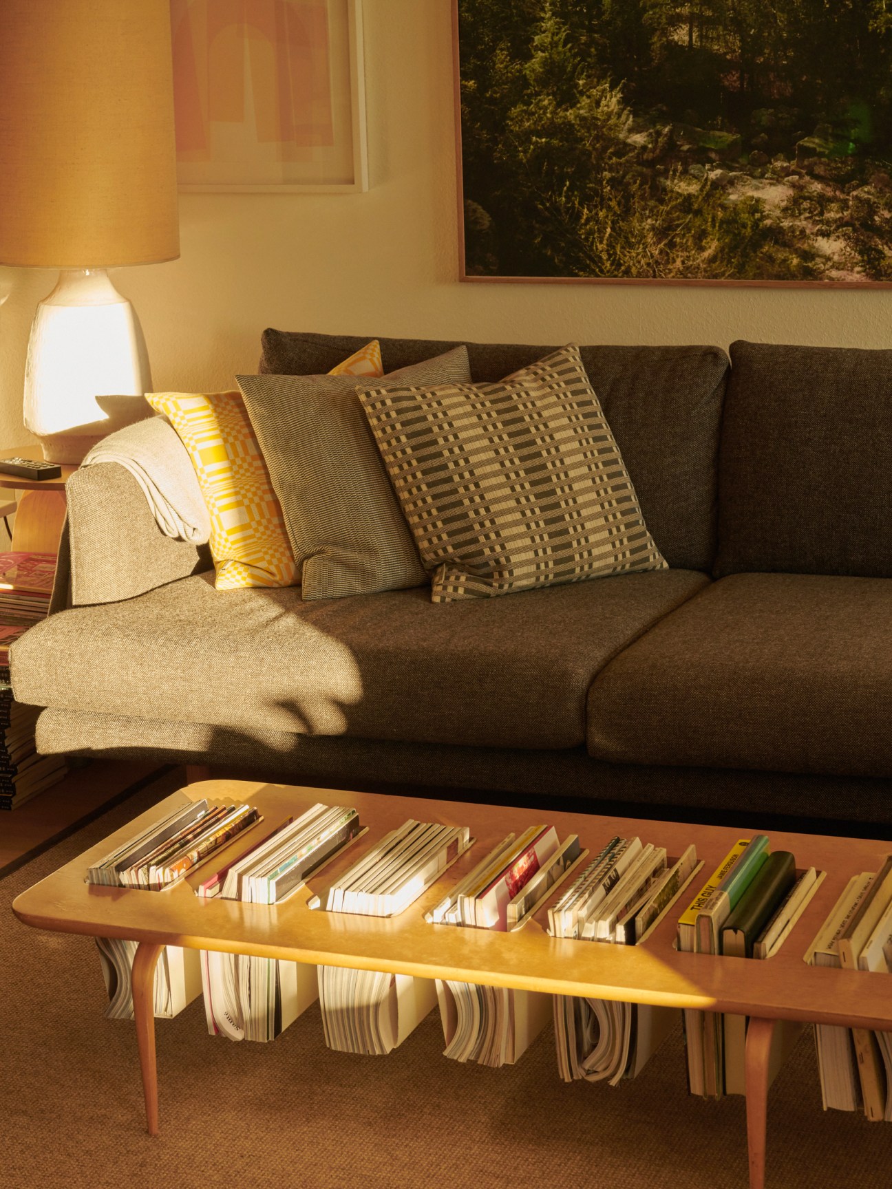 Curved wooden coffee table with magazine storage in front of modern sofa