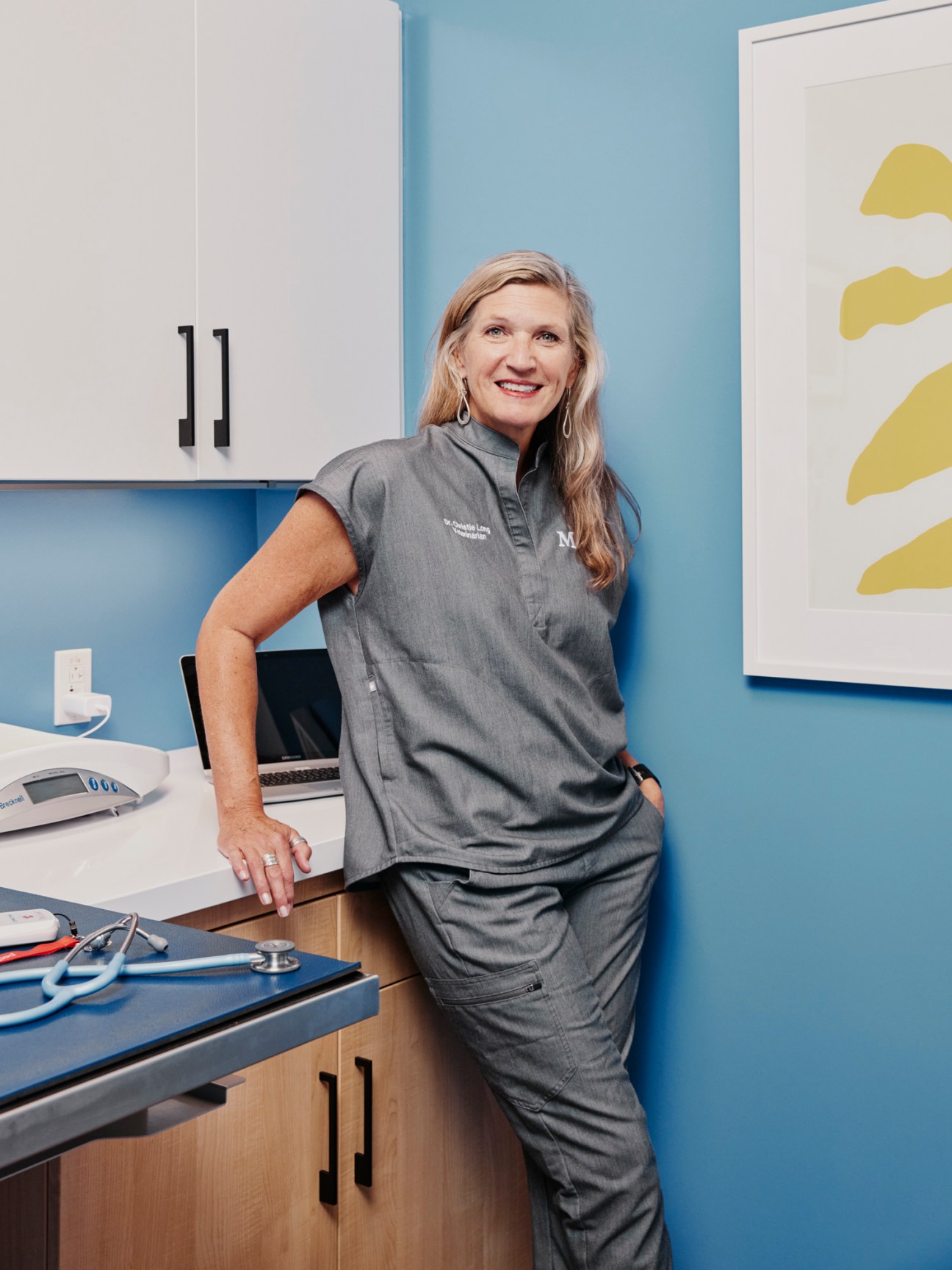 Veterinarian in scrubs leaning against examination table in Modern Animal clinic