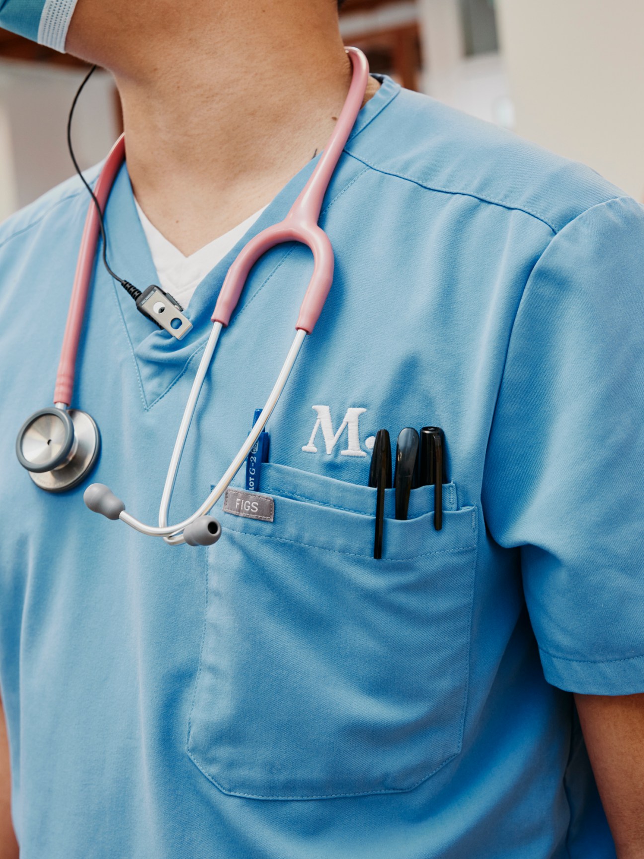 Close-up of a veterinary technician wearing a light blue medical scrub with a stethoscope around their neck.