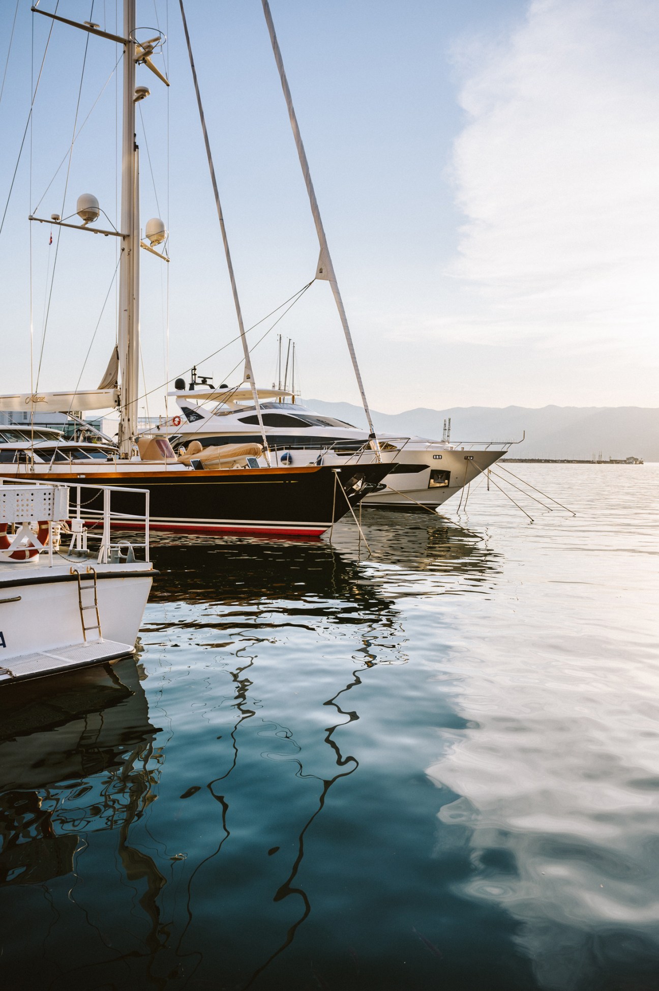 Several sailing boats moored in Rijeka harbour with the city and hills visible in the background
