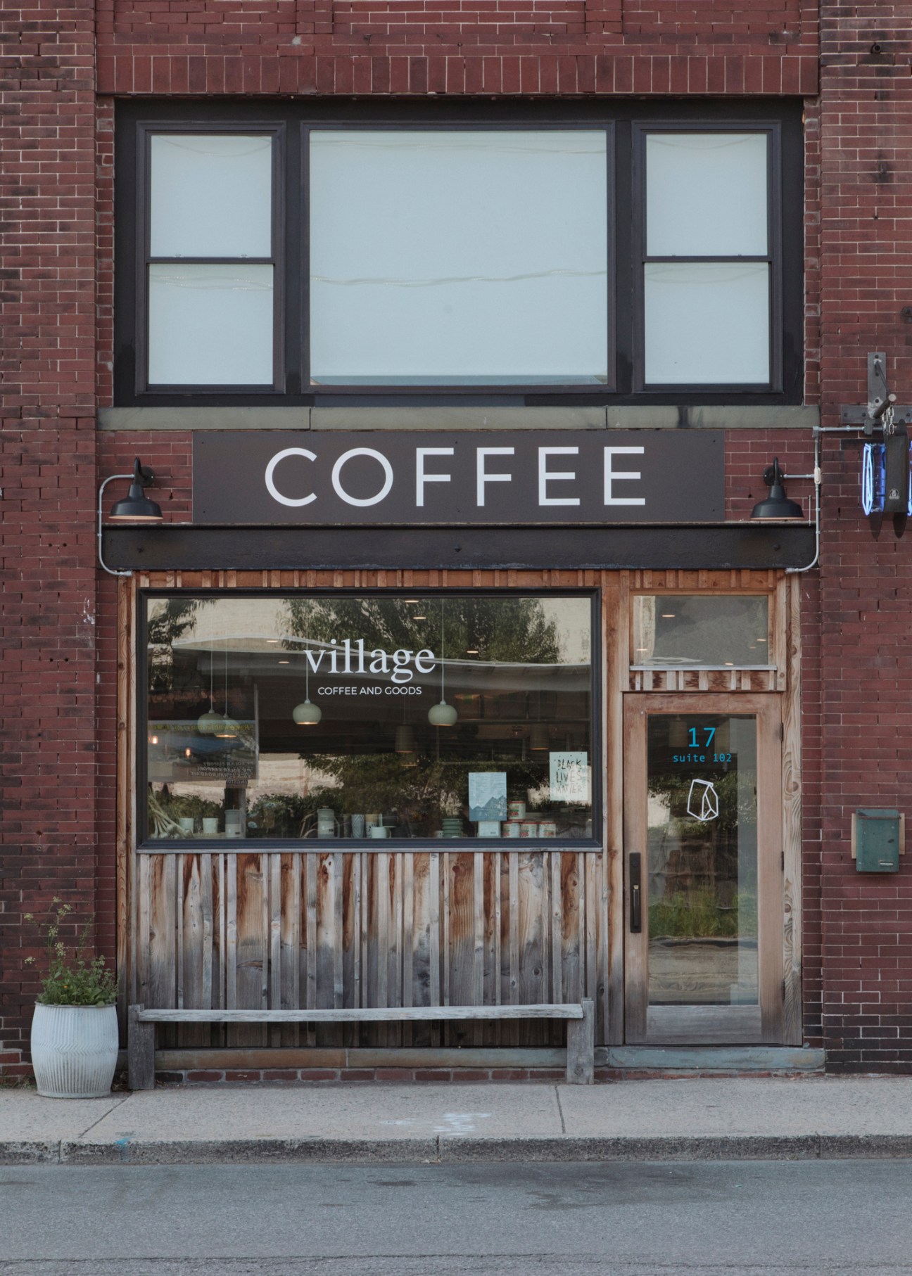 Village Coffee and Goods storefront in Kingston with black signage and wooden window display panel.