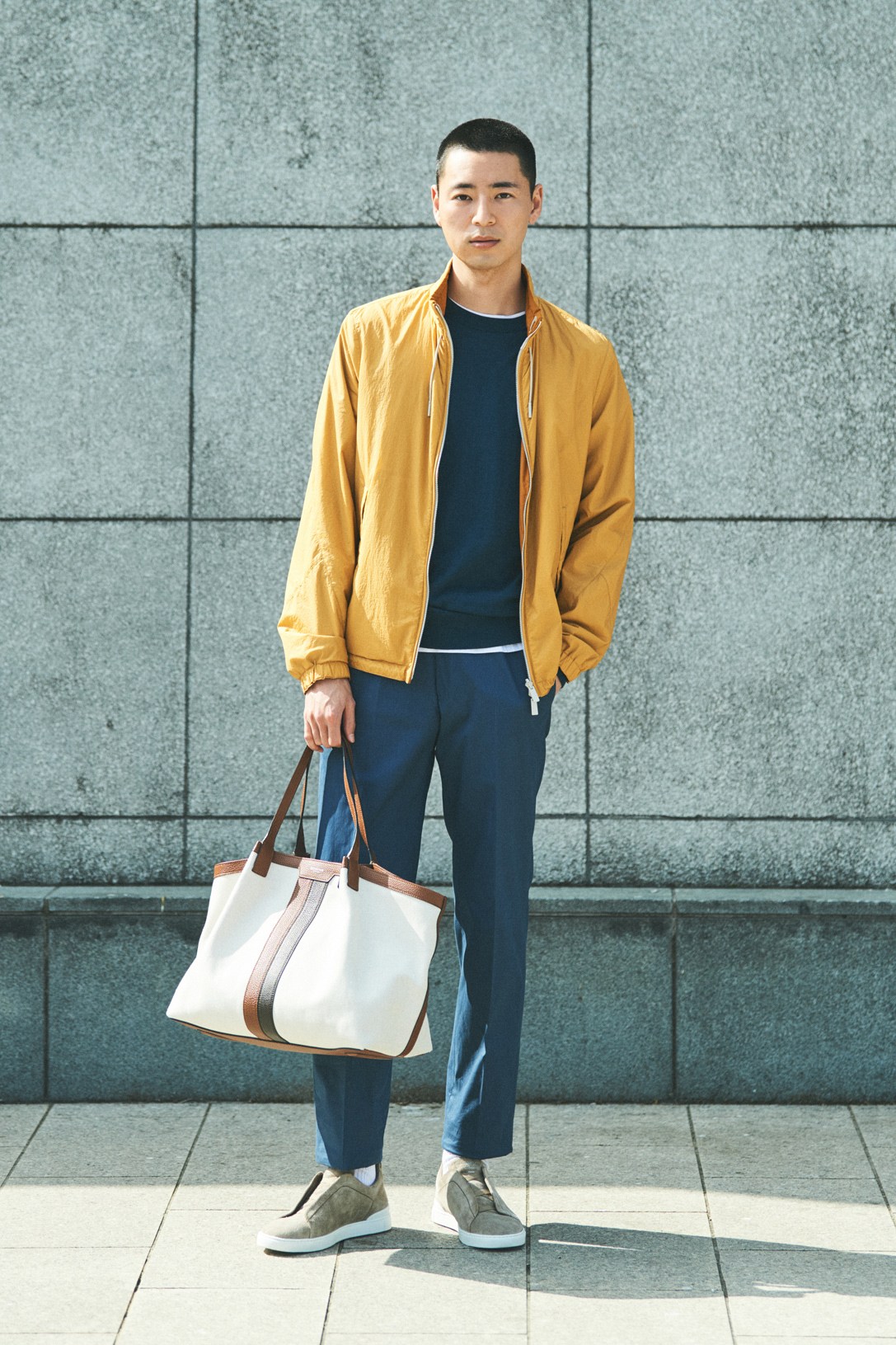 Model wearing Ermenegildo Zegna jacket, jumper, t-shirt and trousers with Serapian bag