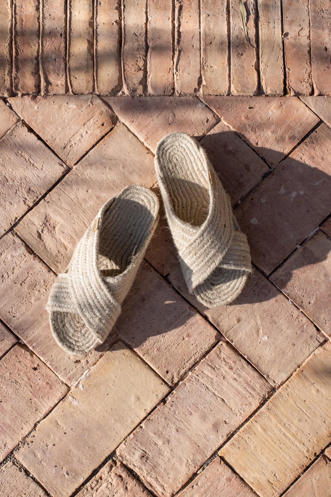 Handwoven rope sandals on terracotta brick flooring showing traditional artisanal craftsmanship