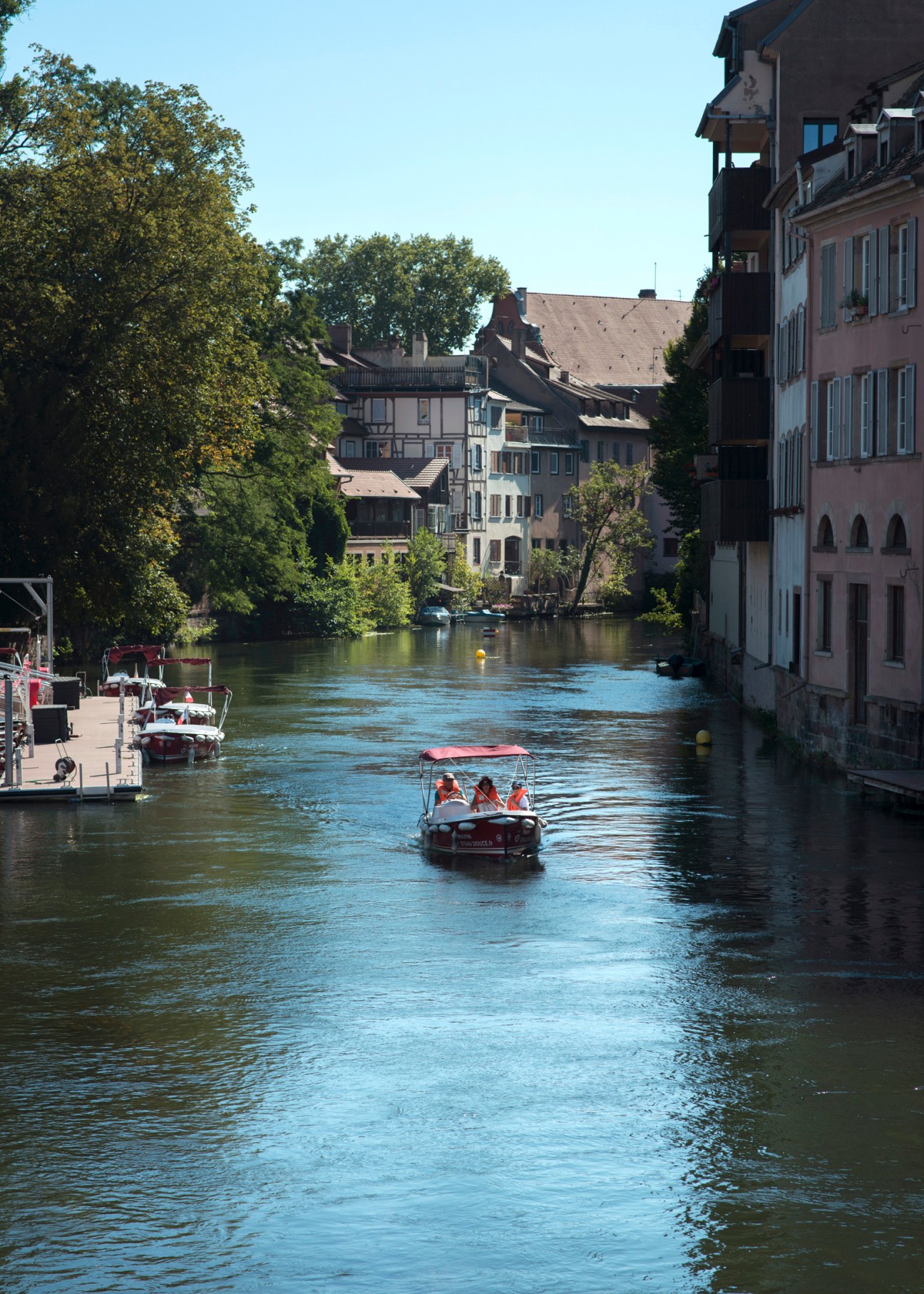 Tourist boat filled with passengers navigating through canal waters in Strasbourg's historic district