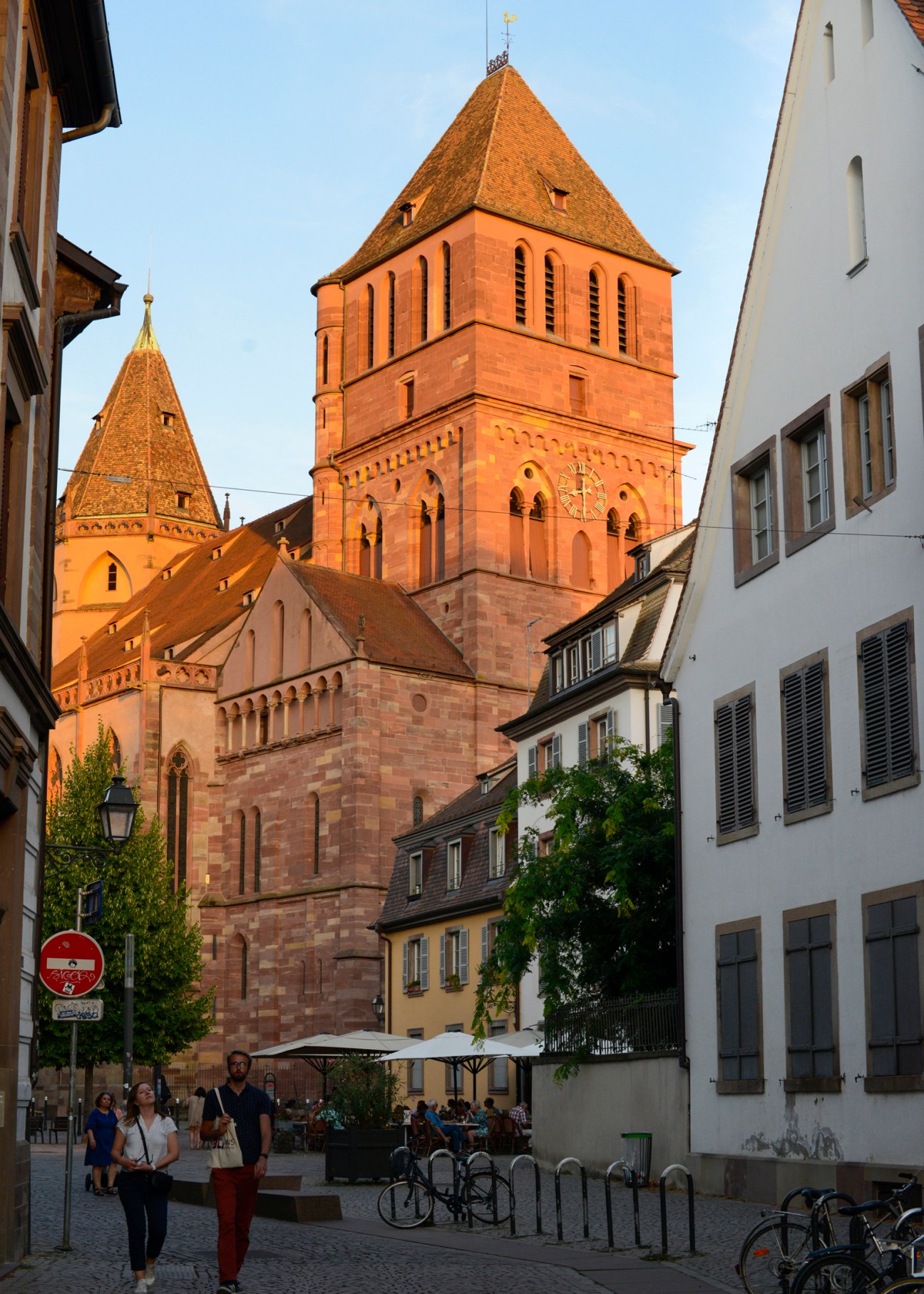 Gothic church with red sandstone towers and pyramidal roofs viewed from cobblestone street in Strasbourg