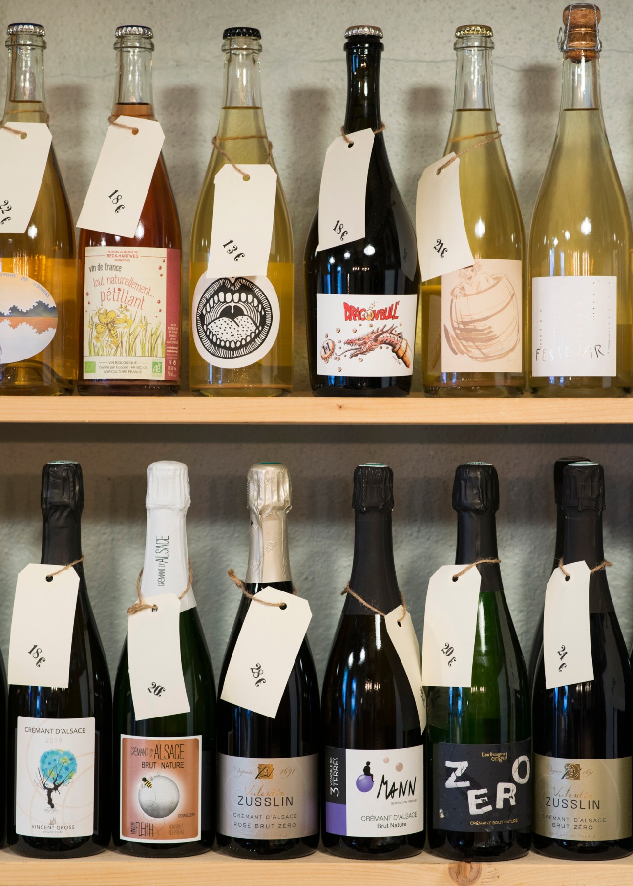 Two shelves of wine bottles with price tags displayed at L'Un des Sens wine shop