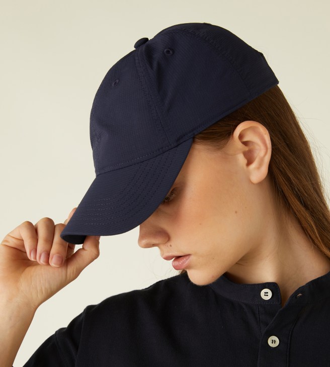 Woman wearing Monocle navy ball cap made from nylon ripstop, shown in profile view.