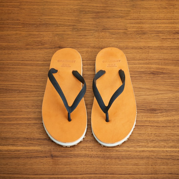 Orange flip-flops with black straps from Spalwart on wooden surface