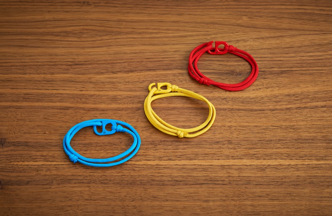 Three colorful wristbands in blue, yellow, and red on a wooden surface
