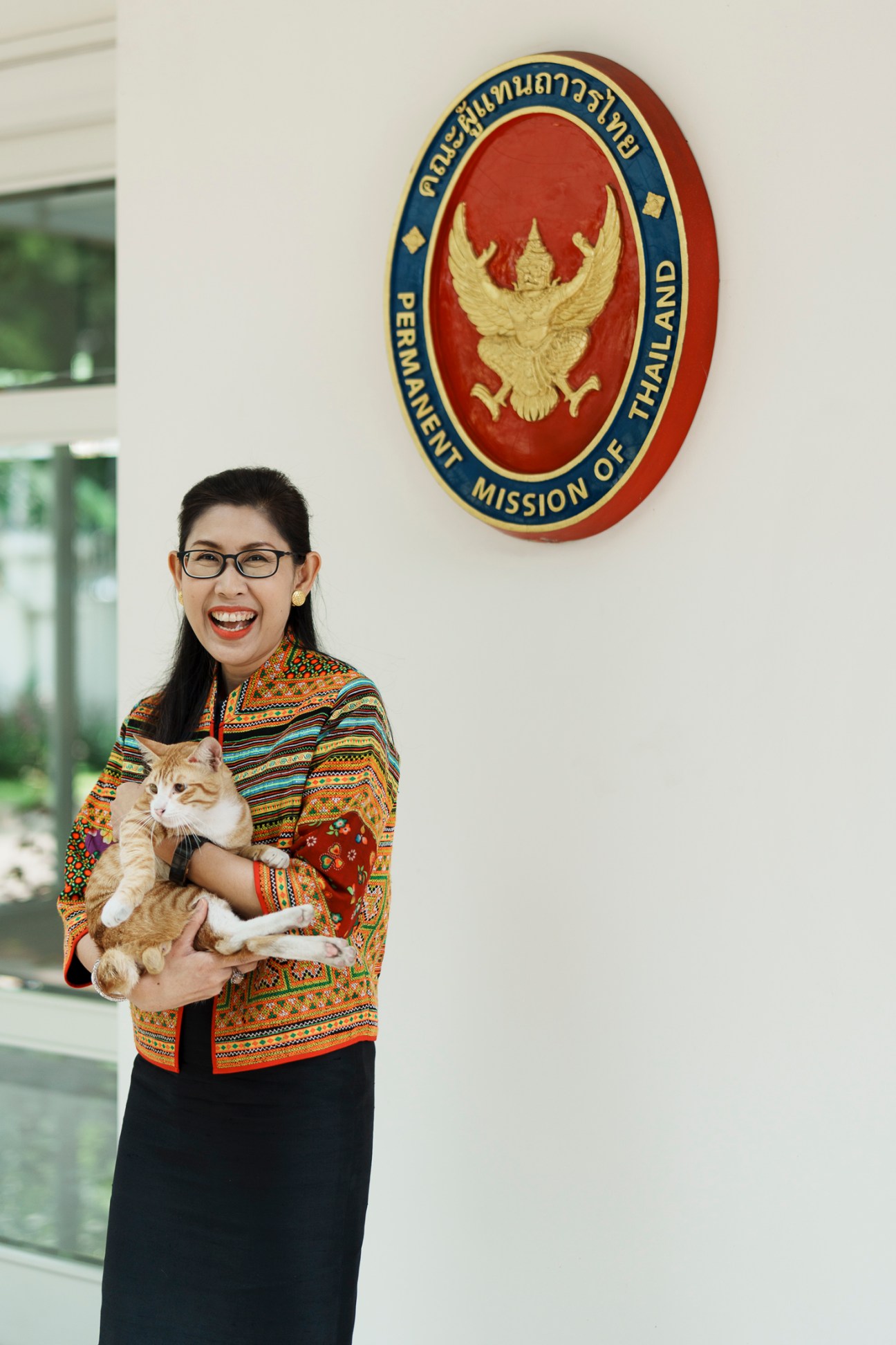 Thailand's ambassador to Asean, Urawadee Sriphiromya, holding an orange and white cat in colorful traditional jacket