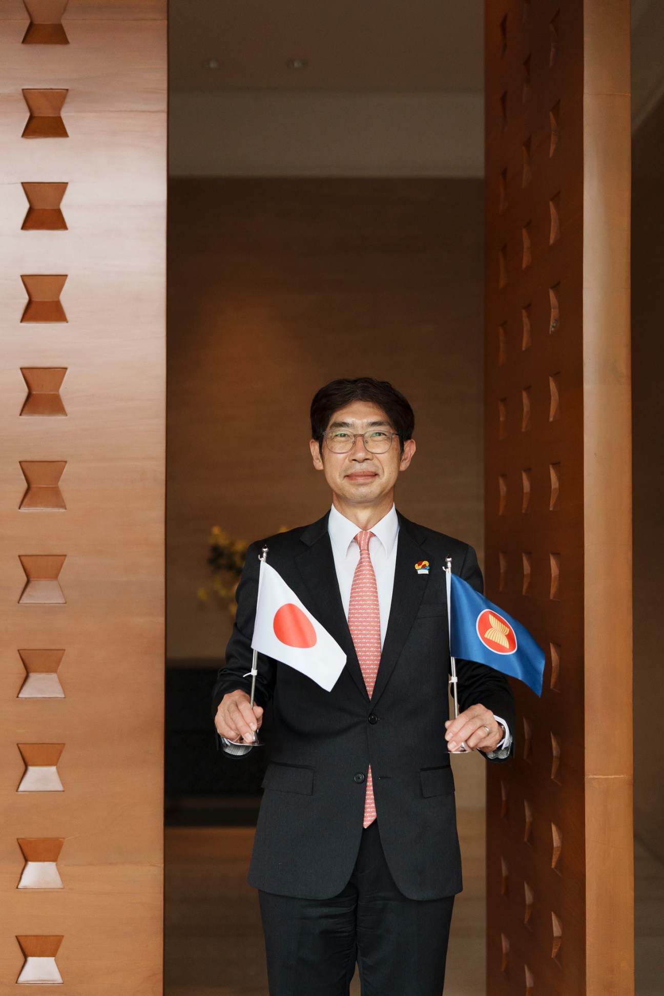 Masahiko Kiya, Japan's ambassador to Asean, holding Japanese and ASEAN flags in formal diplomatic attire