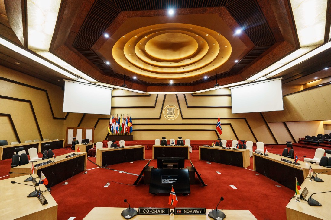Interior view of ASEAN Hall showing tiered seating arrangement with red carpet and wooden desks in a semicircle