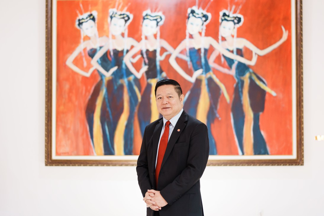 Kao Kim Hourn, Asean's secretary-general, standing in front of a colorful painting of five dancing figures