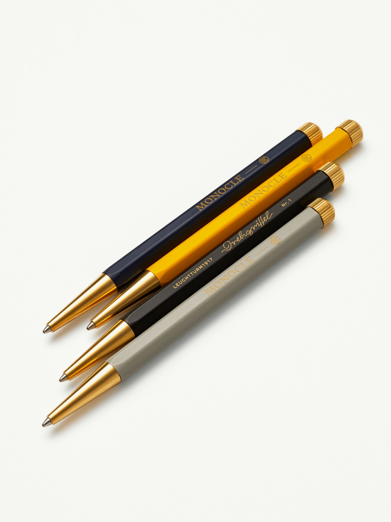 Leuchtturm1917 x Monocle Drehgriffel pens in navy, yellow, light grey and black with brass caps.