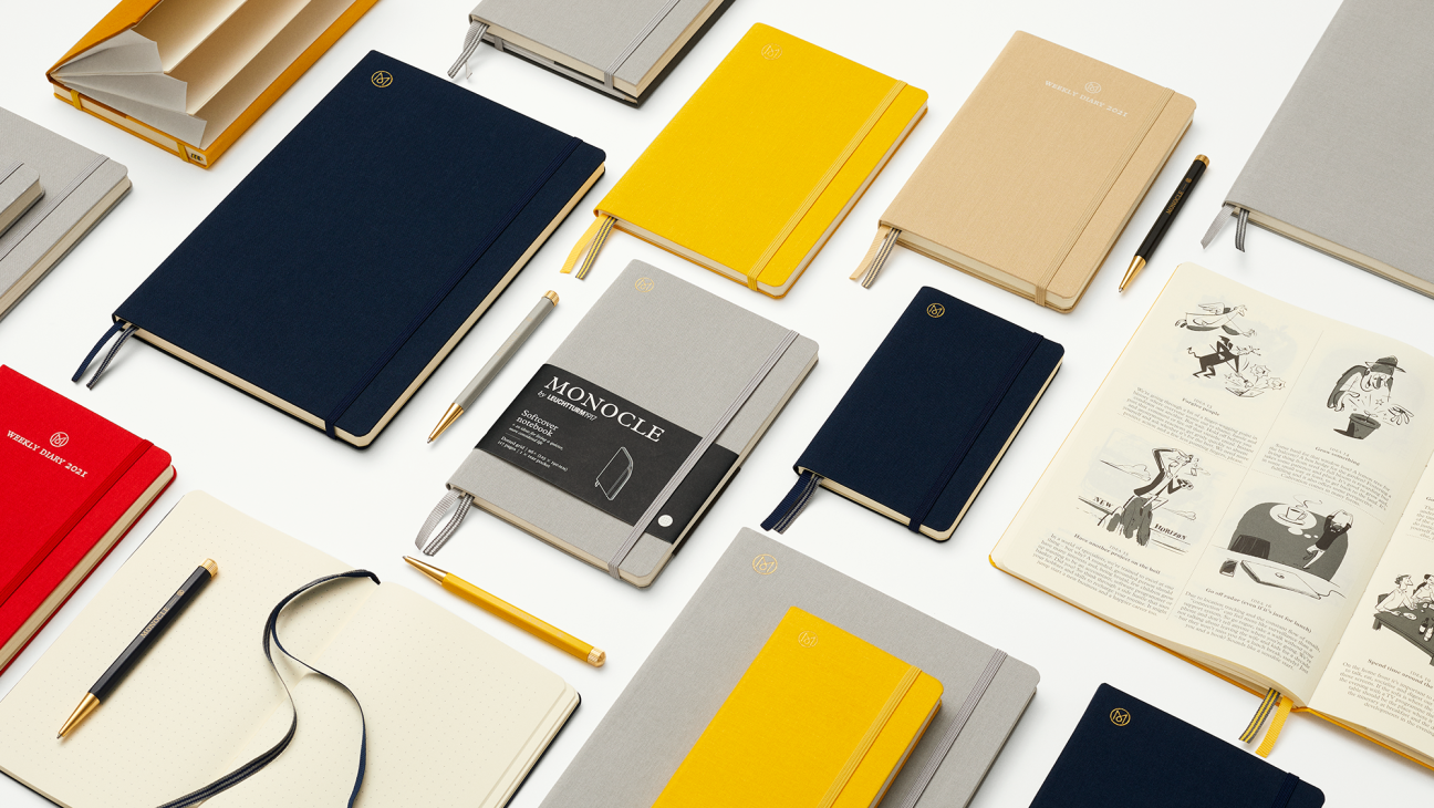 Collection of Monocle x Leuchtturm notebooks in navy, yellow and grey arranged with pens