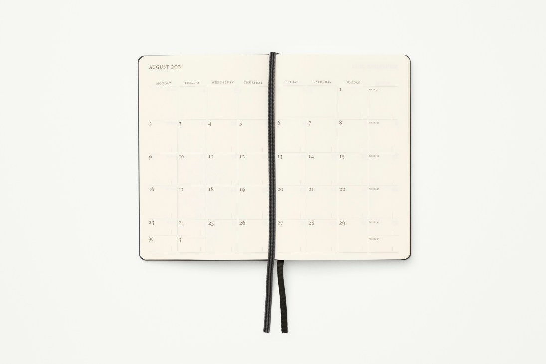 Open black weekly diary showing August 2021 calendar spread with cream colored pages