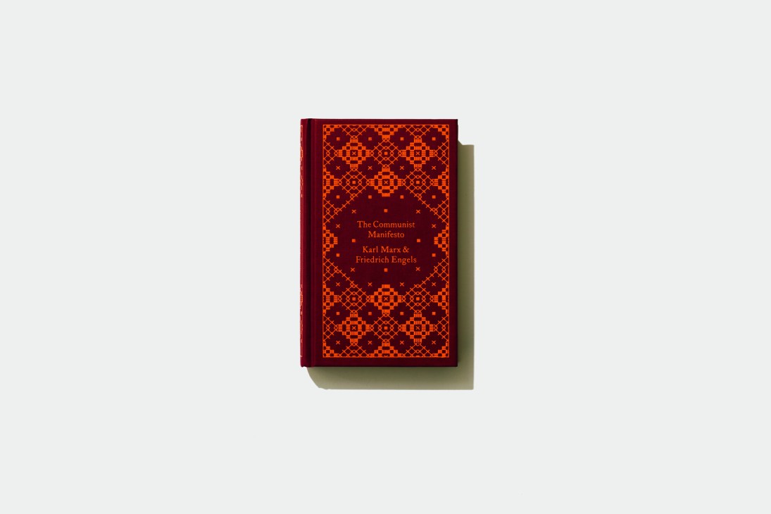 The Communist Manifesto by Karl Marx and Friedrich Engels with red and orange geometric patterned hardcover.