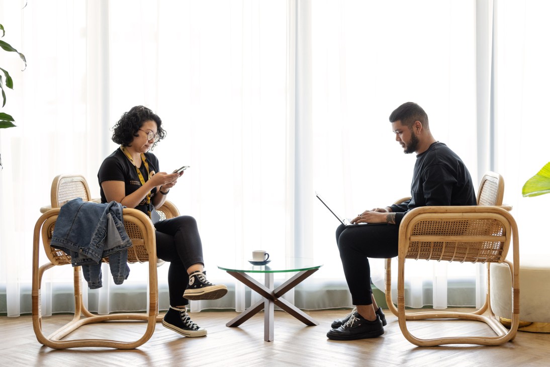 Two men standing in contemporary co-working space with exposed ceiling and modern furniture