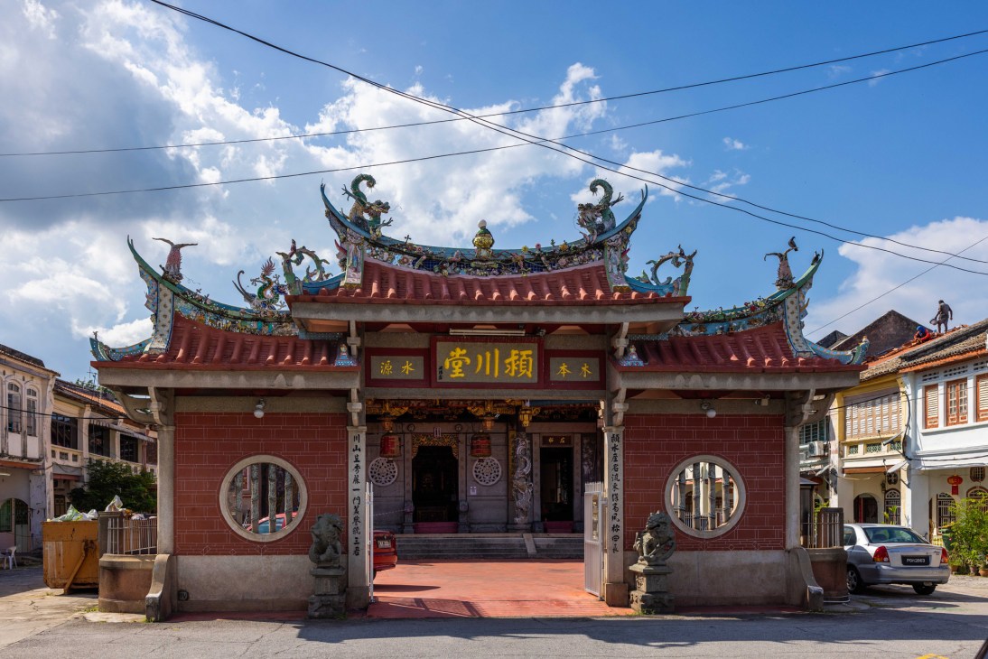 Traditional Chinese temple with ornate red-tiled roofs, decorative dragons, and circular windows in George Town