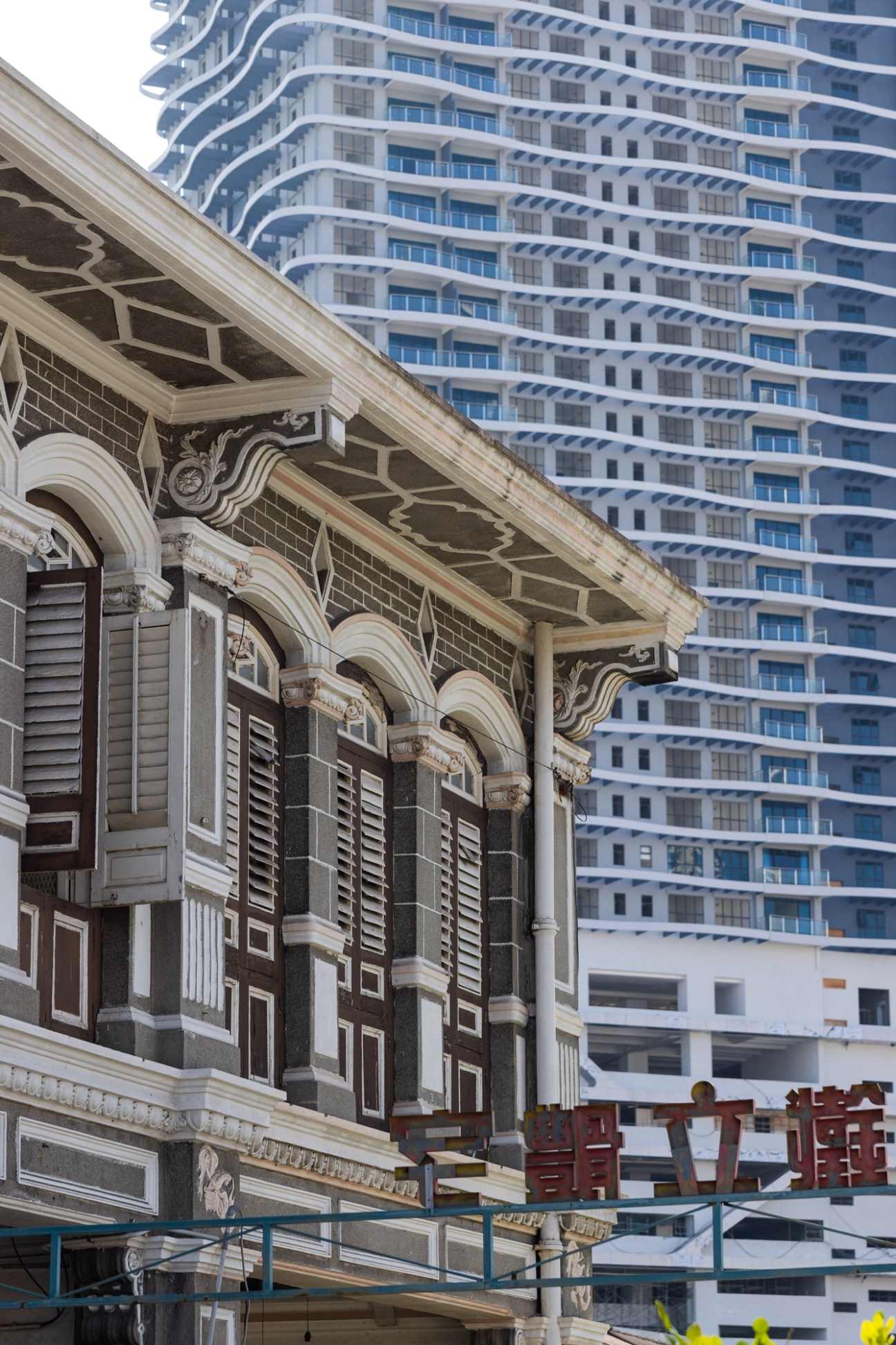 Historic colonial building with ornate facade and columns contrasting against modern high-rise apartment towers