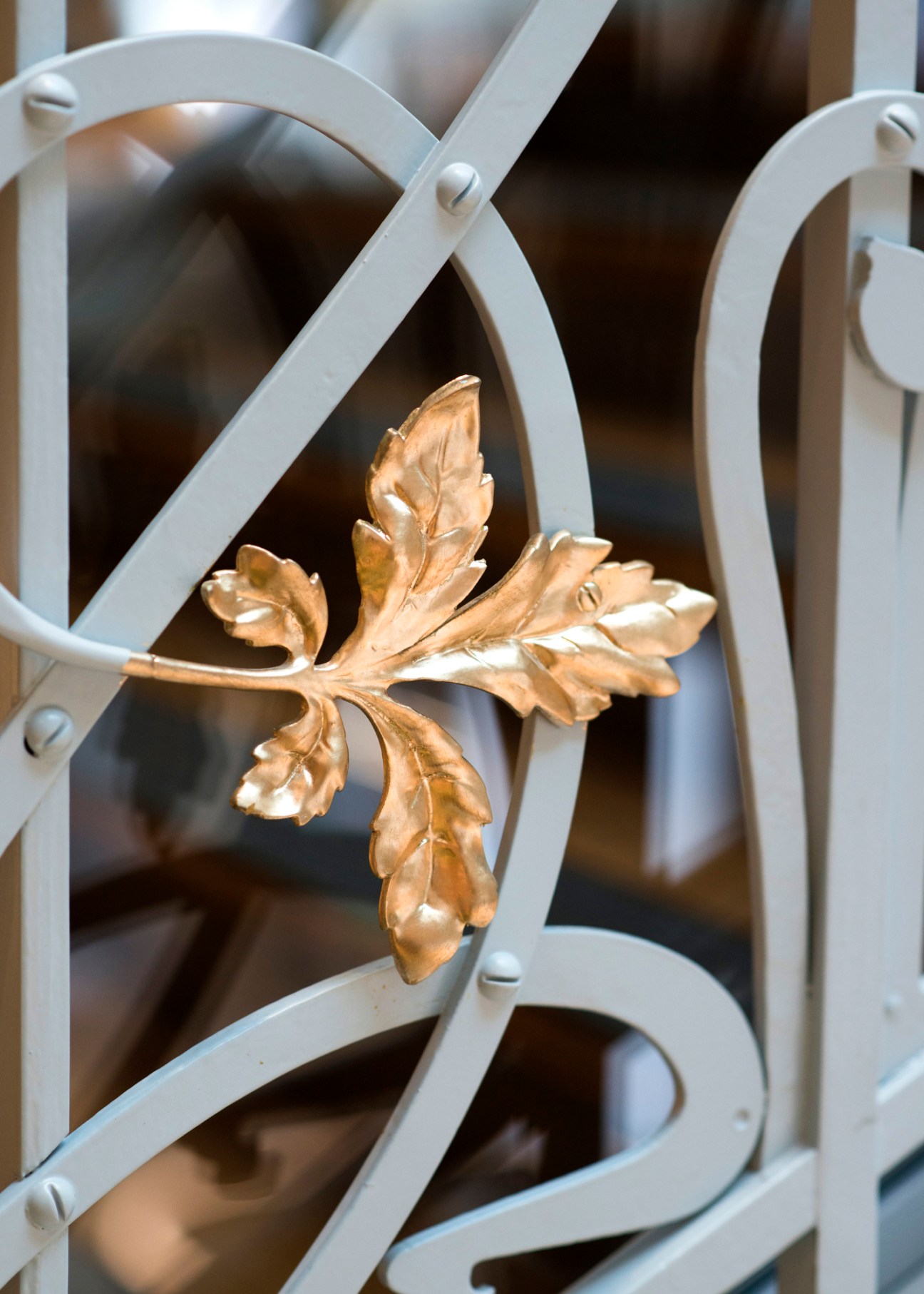 Ornate golden leaf detail on white painted metal ironwork of a renovated staircase