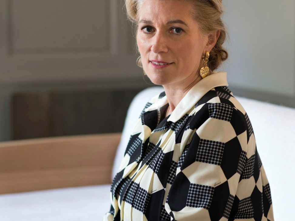 Marie-Claire Daveu sits at a wooden table wearing a geometric patterned black and white blouse