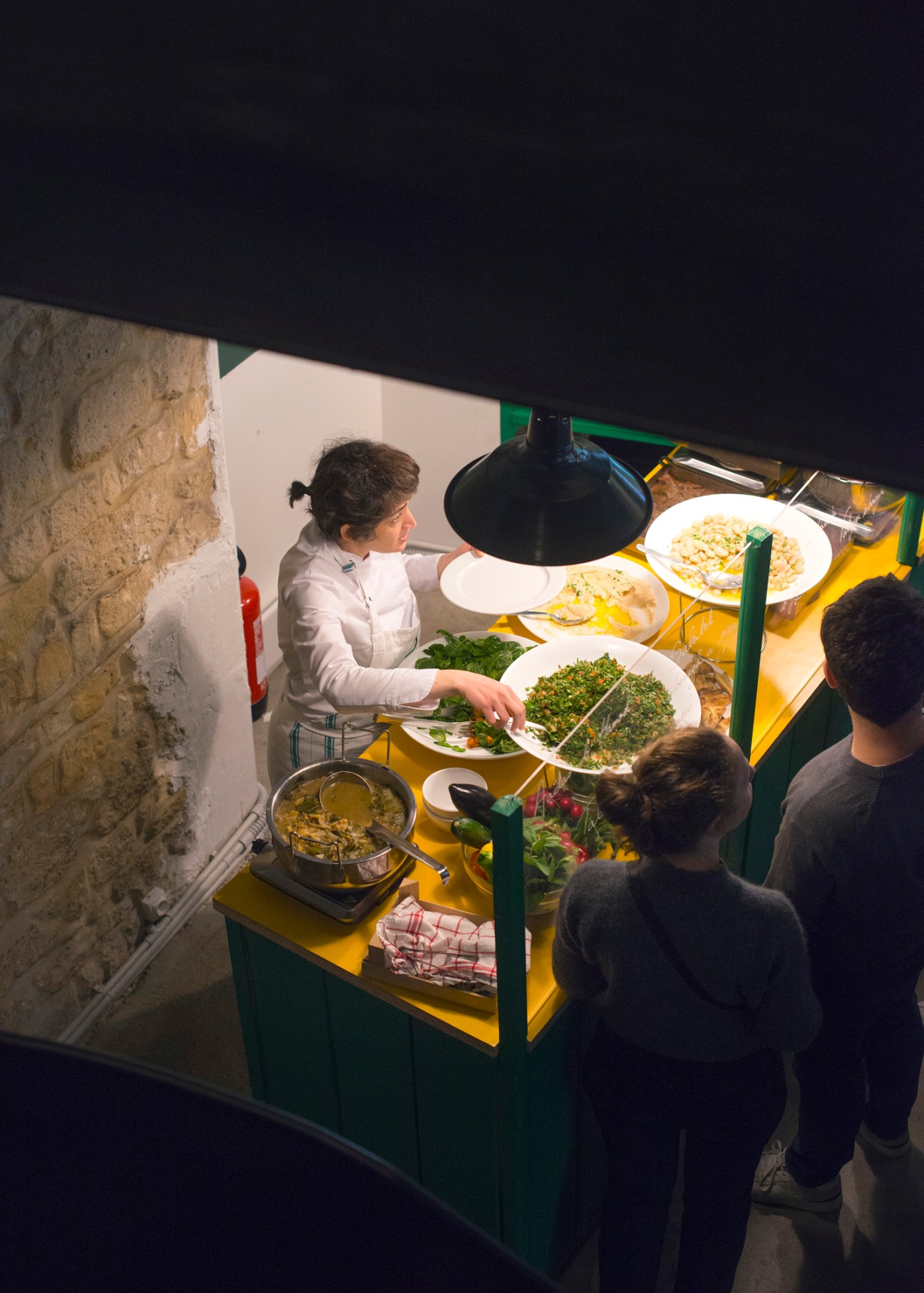 Staff member serving food from the buffet at Tawlet Paris
