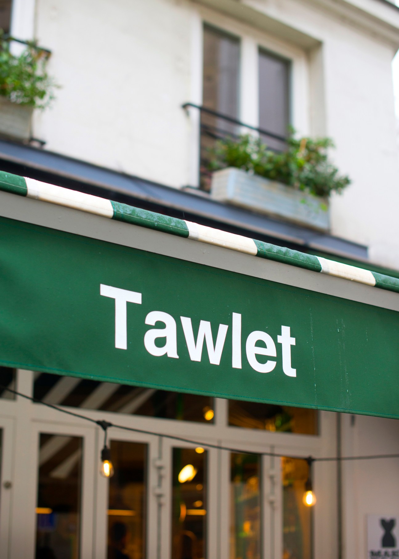 Green and white striped awning above storefront of Tawlet restaurant