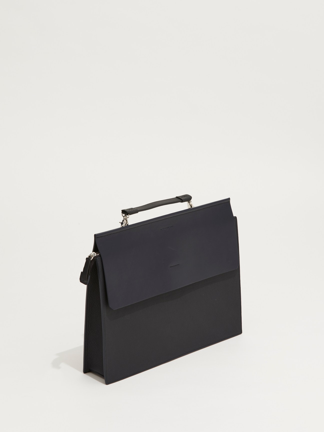 Black leather briefcase by Nosakhari with top handle and front flap closure on neutral background