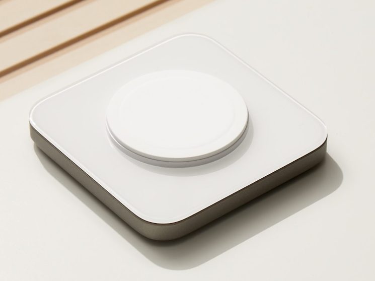 Nomad Base One MagSafe Charger with white glass top and metal base on wooden surface
