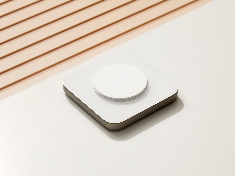 Nomad Base One MagSafe Charger with white glass top and metal base on wooden surface