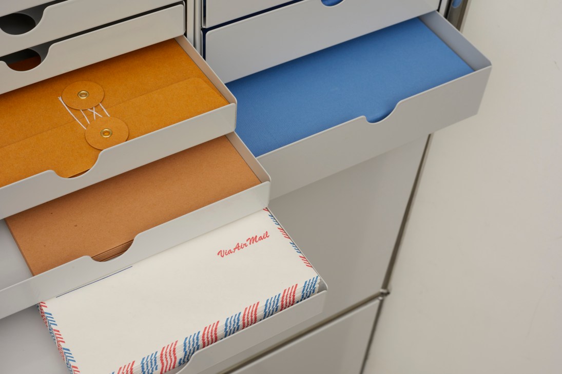 Reusable washer envelopes with string fastenings and airmail envelopes with red and blue striped borders in storage boxes.