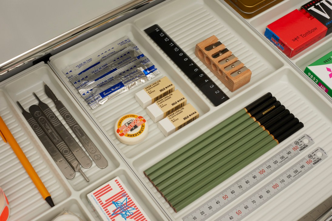 Organised drawer of stationery items including pencils, rulers, erasers, and design tools.