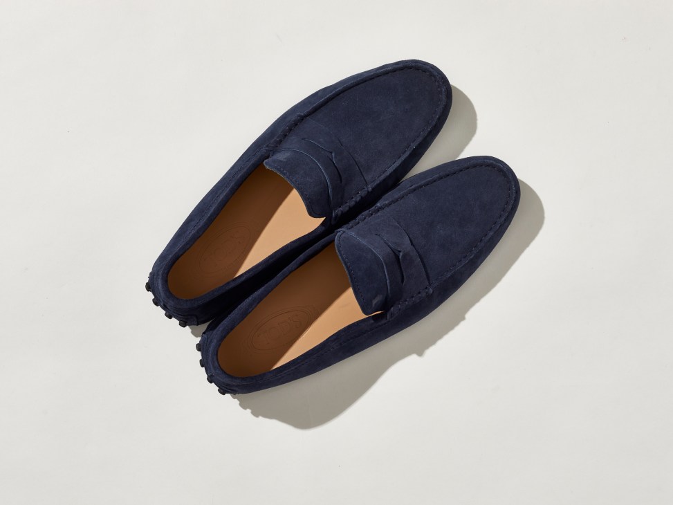 Navy blue suede driving shoes by Tod's with rubber pebble sole photographed on white background