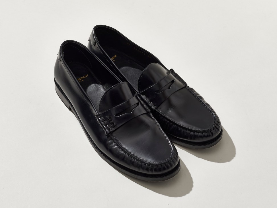 Black leather penny loafers by Saint Laurent on white background