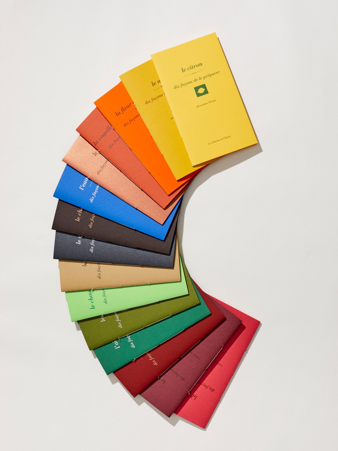 Collection of Dix façons de le préparer cookery books showing their distinctive coloured cardboard covers bound with linen thread