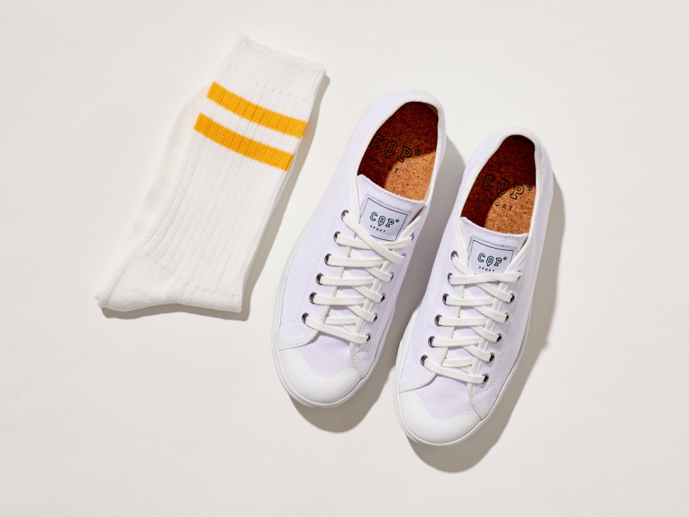 White CQP Sport trainers and white tube socks with yellow stripes on light background