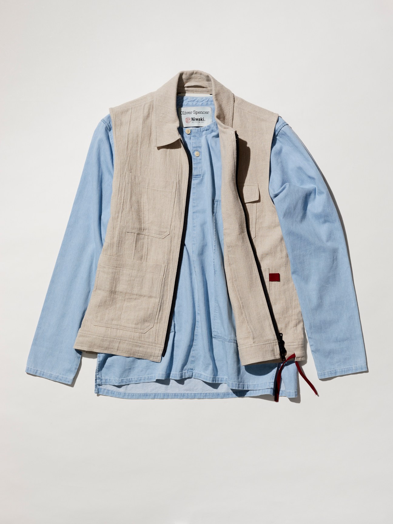 Niwaki x Oliver Spencer beige utility vest with multiple pockets layered over light blue shirt
