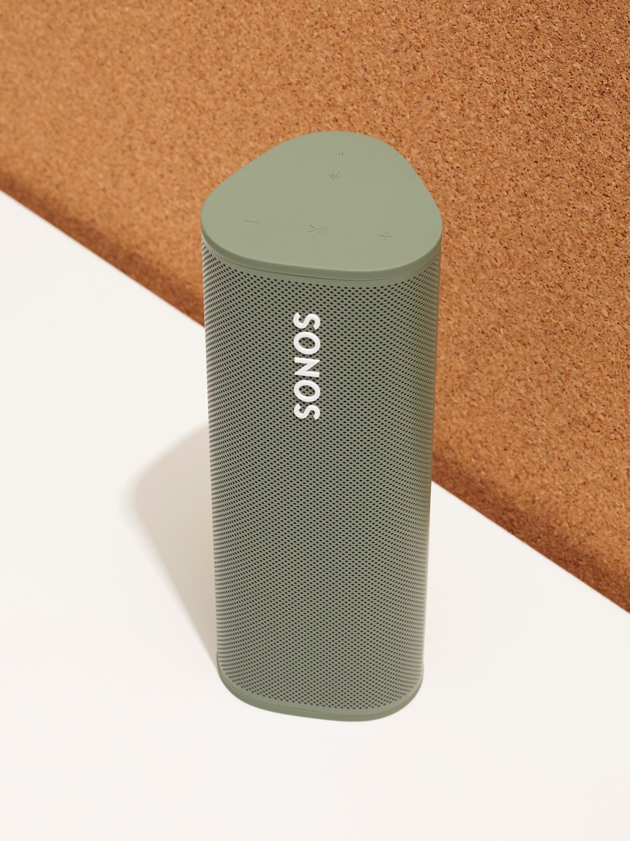 Sonos Roam portable Bluetooth speaker in olive green color on white and cork surface