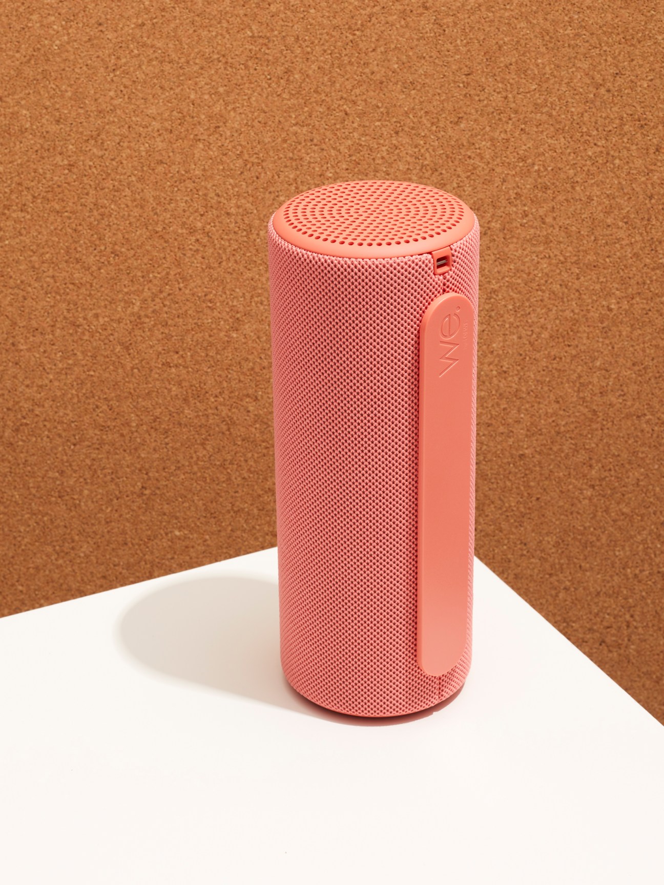Loewe We Hear 1 cylindrical Bluetooth speaker in coral red finish on white surface