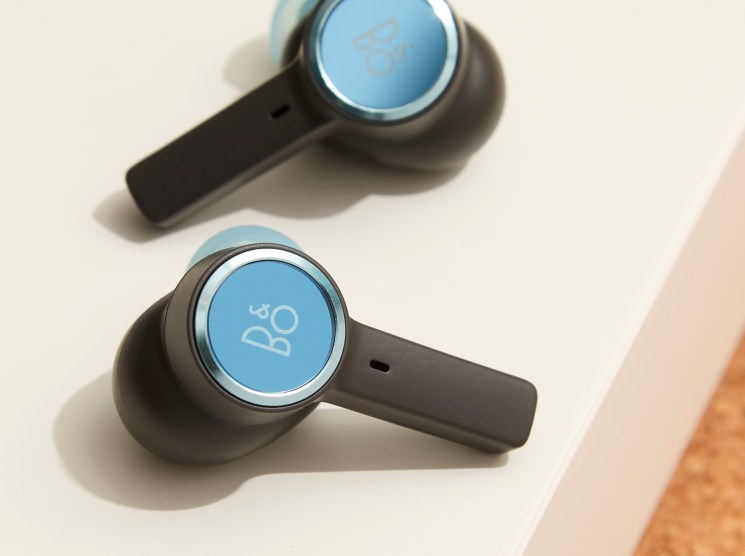 Bang & Olufsen Beoplay EX wireless earbuds with blue circular face plates and black stems on white surface