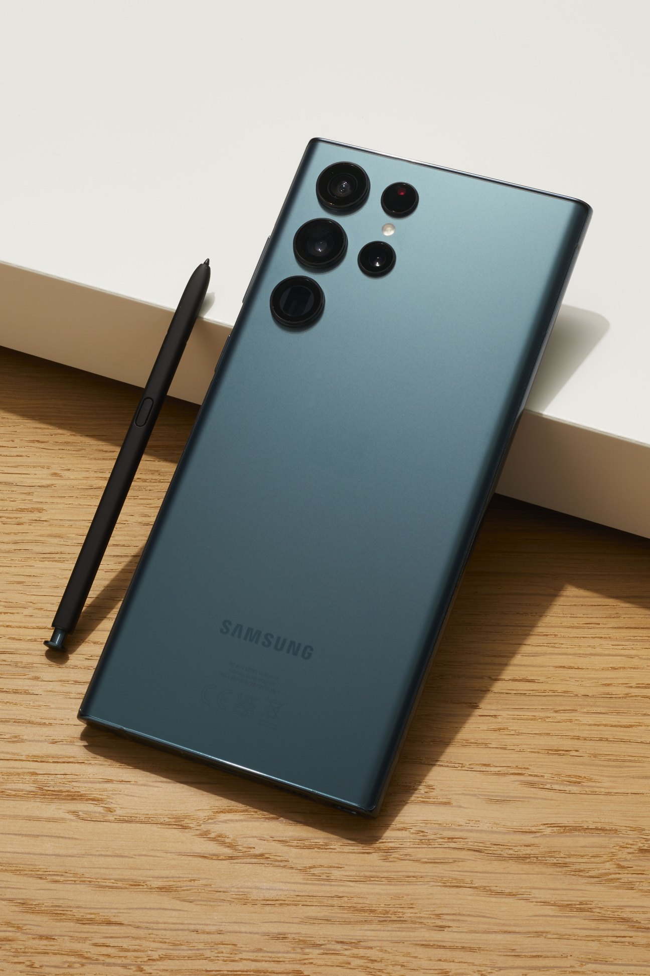 Samsung Galaxy S22 Ultra smartphone in matte green finish with stylus on wooden surface