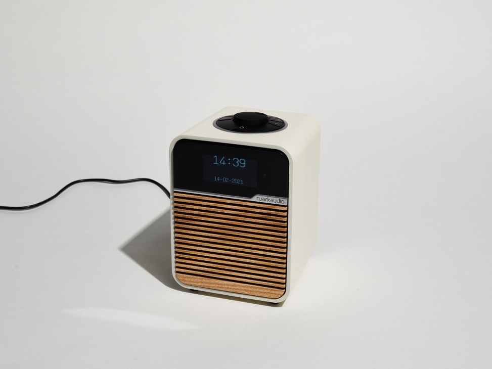 Ruark Audio radio with cream body, black digital display showing time, and wooden striped front panel.