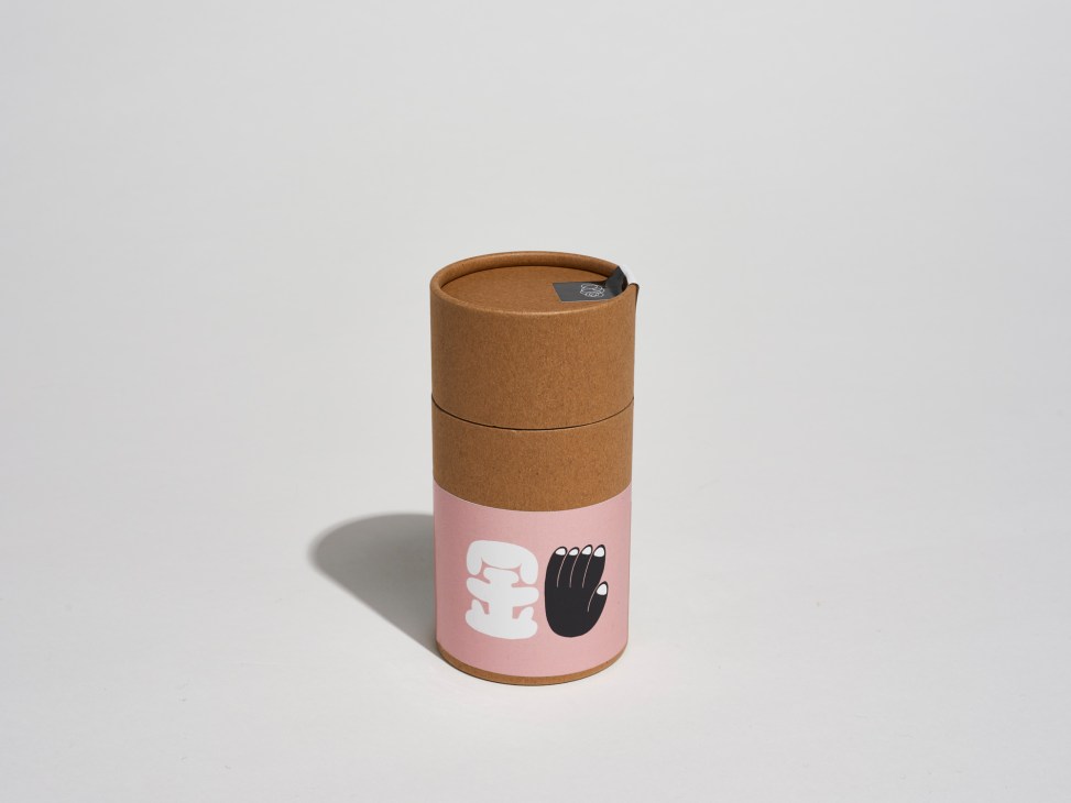 Black Cloud Tea packaging with cork top and pink label featuring white and black hand graphics.