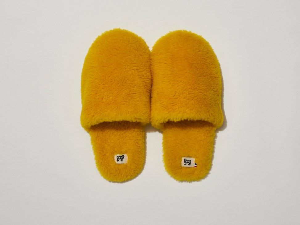 Pair of yellow fuzzy slippers by Toasties against a light background.